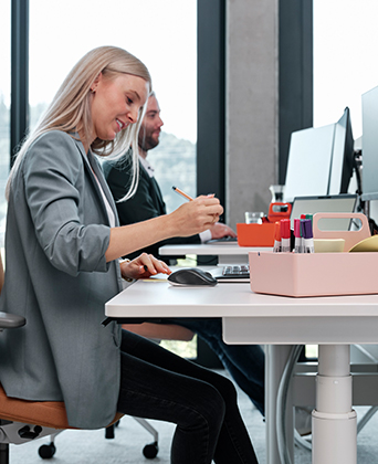 Bürobedarf im STREIT Shop Mitarbeiterin von Streit Service & Solution sitzt am Schreibtisch und schreibt etwas auf