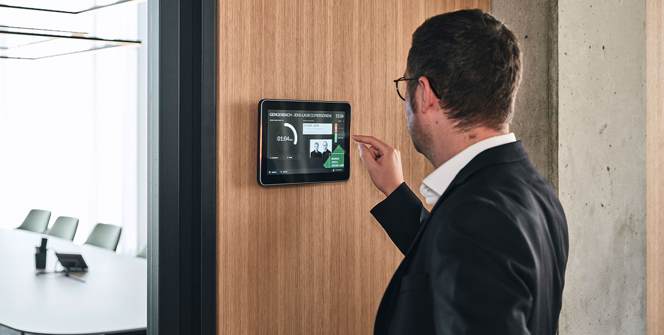 Intelligentes Raumbuchungssystem Mitarbeiter von Streit Service & Solution bedient das Raumbuchungspanel vor dem Konferenzraum