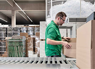 Ist Luftpolsterfolie im Verpackungsbereich noch zeitgemäß? Mitarbeiter von Streit Service & Solution packt im Logistikzentrum ein Packet mit Luftposterfolie