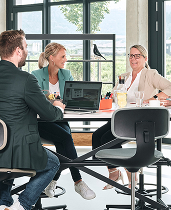 Büroeinrichtung im STREIT Shop Mitarbeiter von Streit Service & Solution sitzen zusammen an einem TIsch und arbeiten miteinander